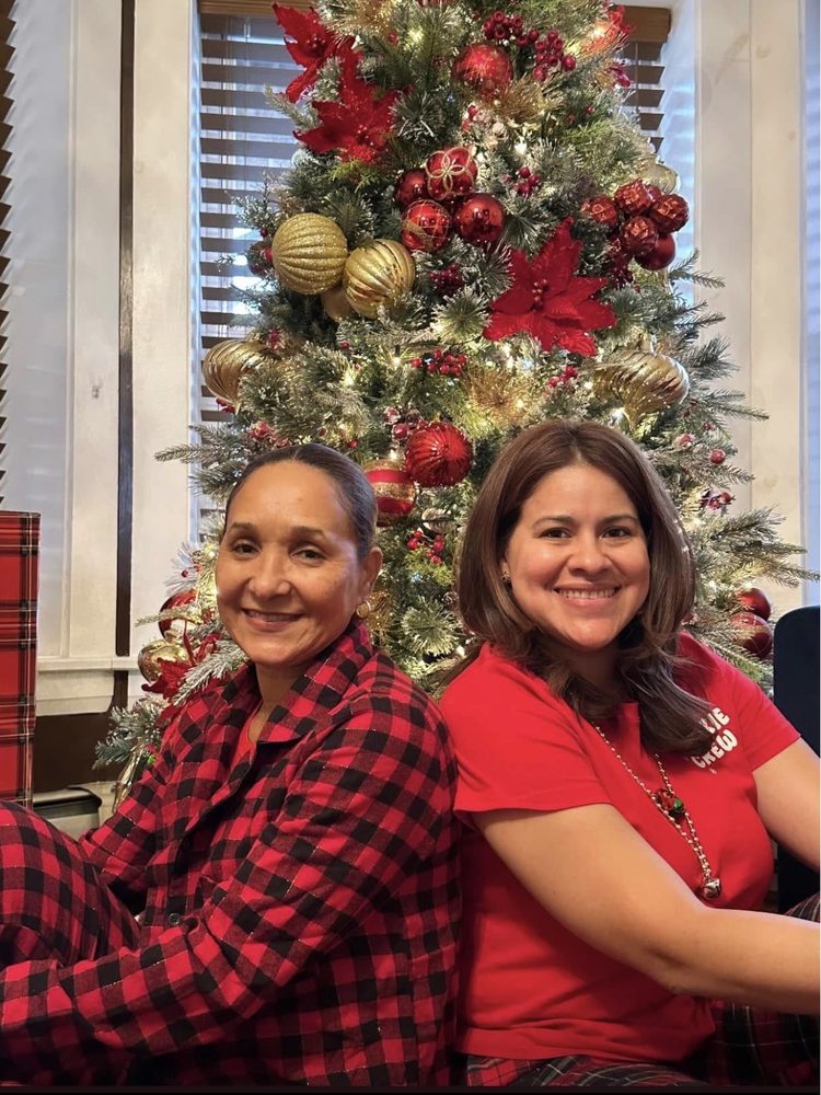 Two Kirsis' Daycare team members smiling together in front of a decorated Christmas tree