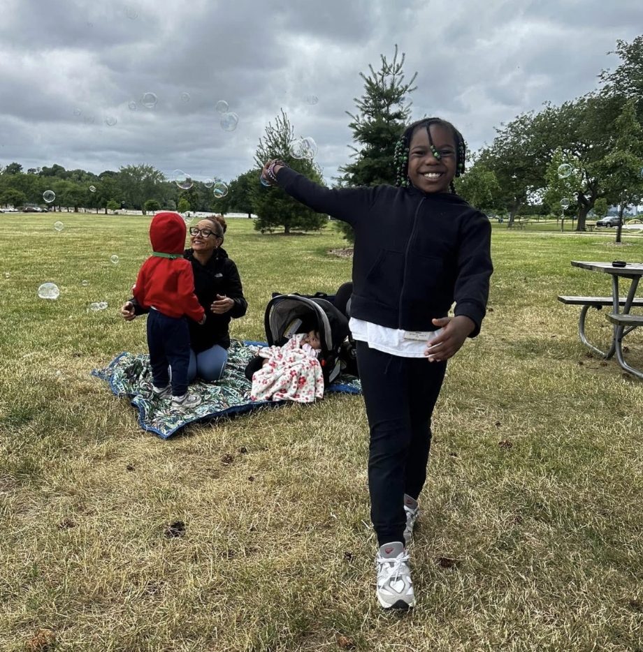 Child blowing bubbles outdoors at a park picnic area during a field trip to Lake Erie Park